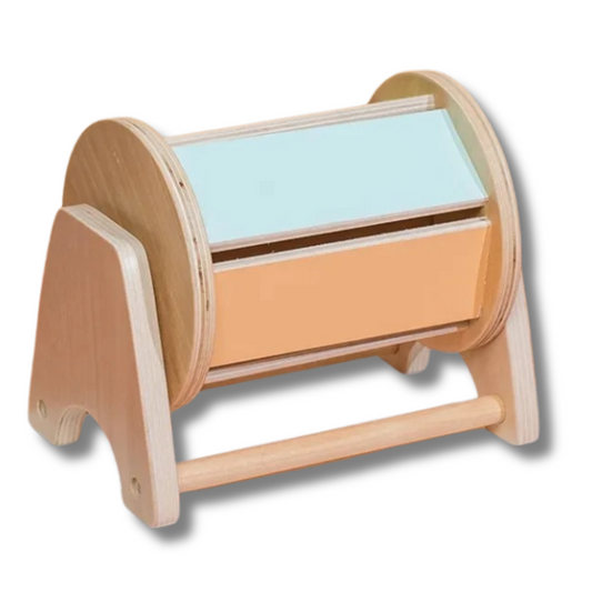 Spielzeug nach dem Montessori Prinzip inspiriert in Form einer Drehtrommel aus Holz mit einer Kugel im Inneren, welches das Baby oder Kind dazu stimuliert die Trommel zu drehen. Dadurch kann gut die Tummy Time gefoerdert werden um die Nackenmuskulatur des Babies oder Kindes zu entwickeln