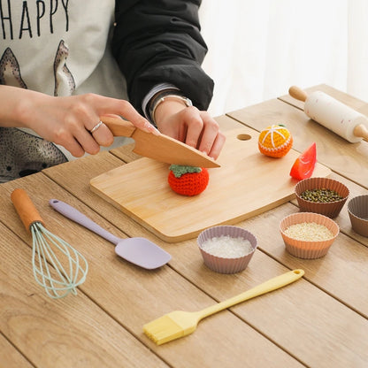 Buntes Kochset aus Holz für Kinder ab 3 Jahren, bestehend aus Löffel, Messer, Schneidebrett und mehr. Das Spielzeug lädt zum kreativen Rollenspiel ein und fördert die Feinmotorik in der Kinderküche.